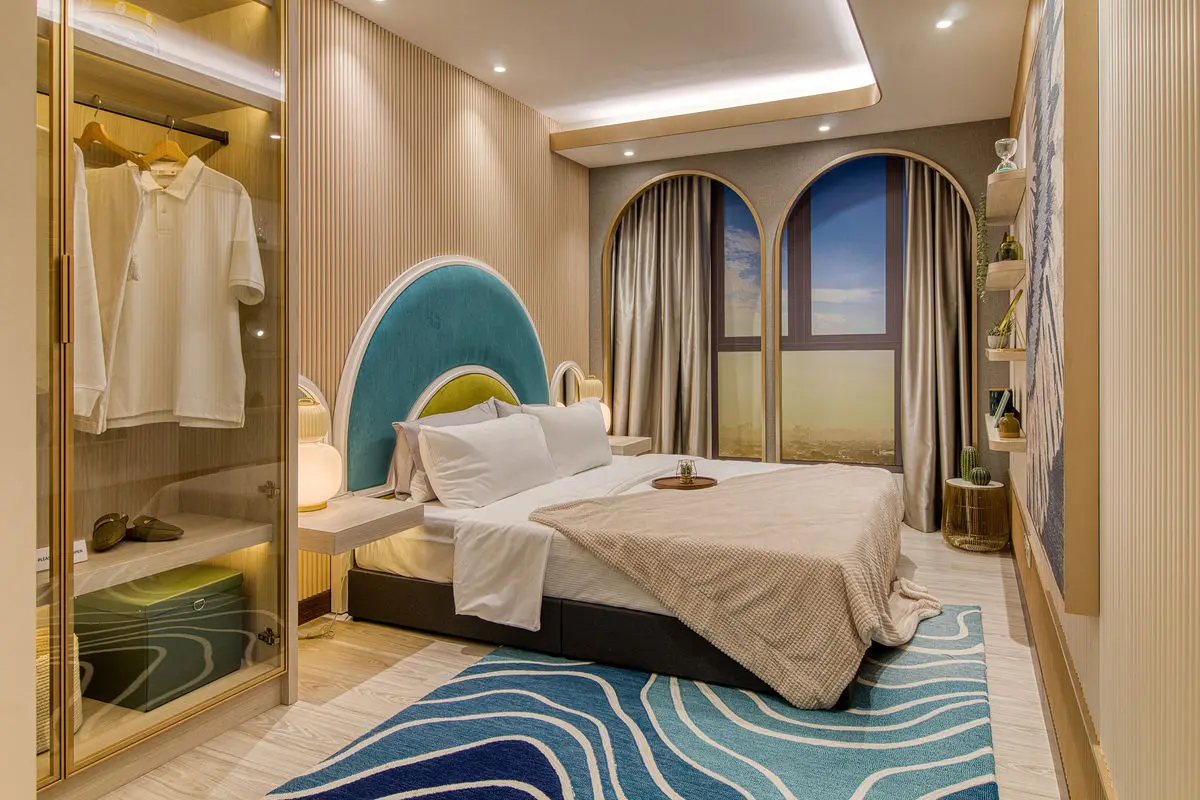 Bedroom with an arched teal headboard, mirrored wardrobe and a wave-patterned rug