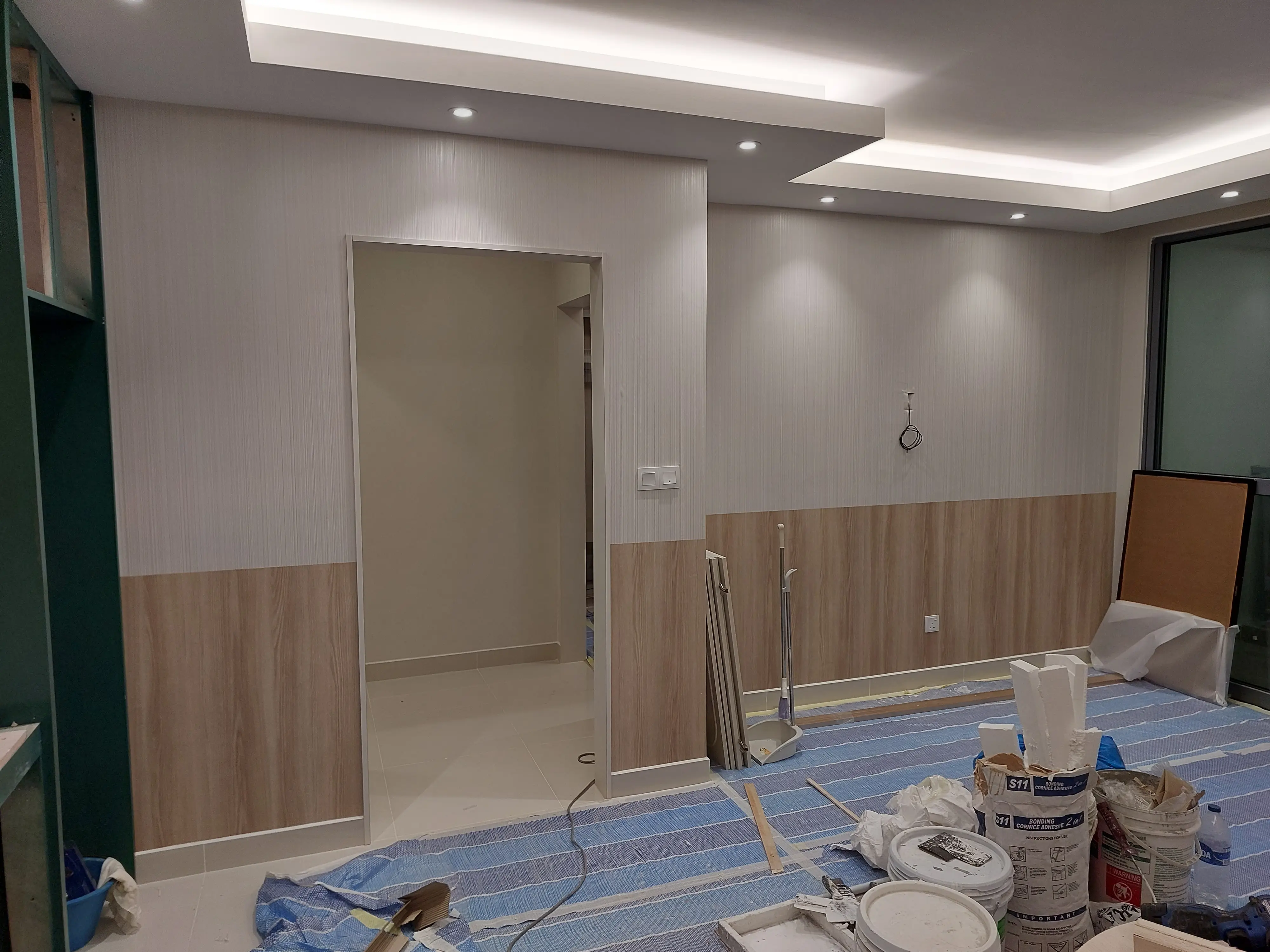Neutral room with wood-effect dado, textured wallcovering, coved LED ceiling and cornice adhesive bags stacked