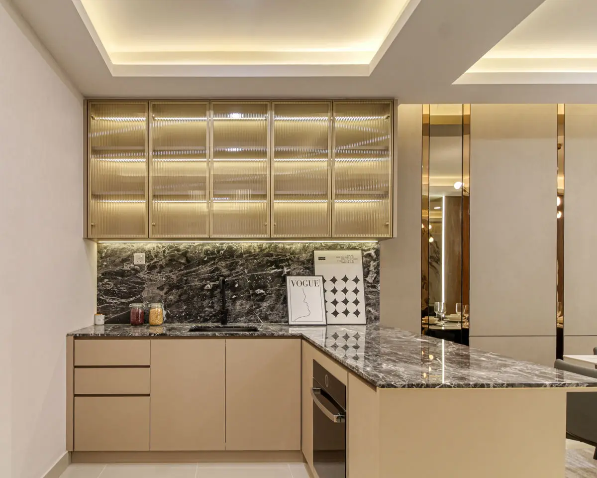 Kitchen with cream cabinetry, brass-framed upper doors and a dark marble worktop