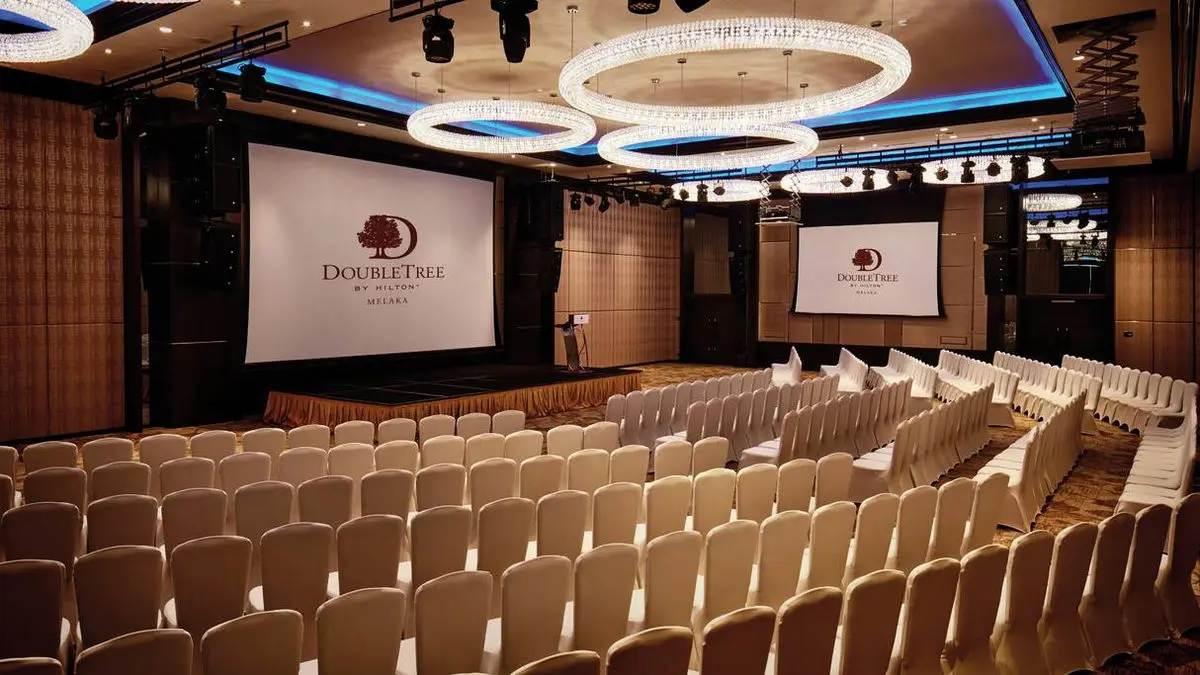 Auditorium with tiered seating, a projection screen and ring ceiling lights
