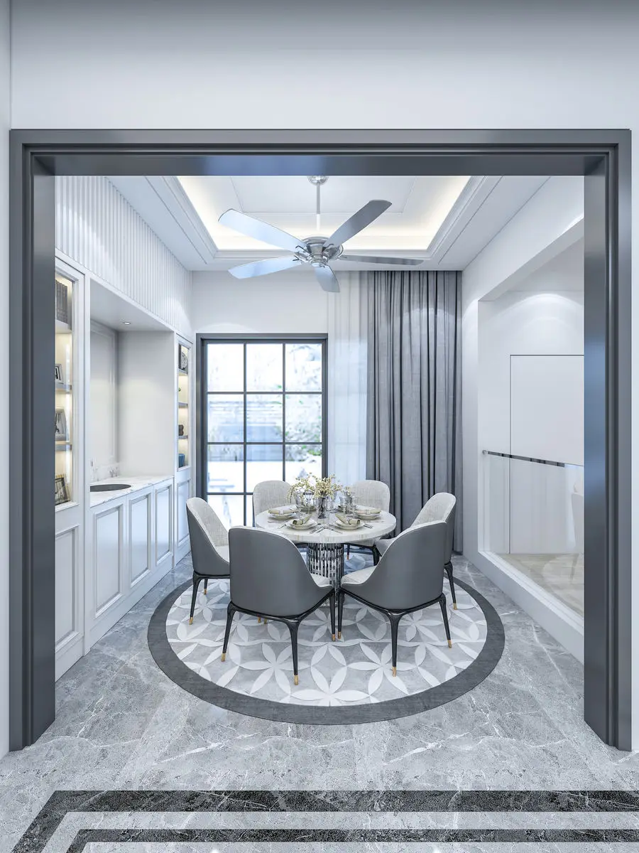 Dining area with a round table and grey chairs on a patterned marble floor inlay