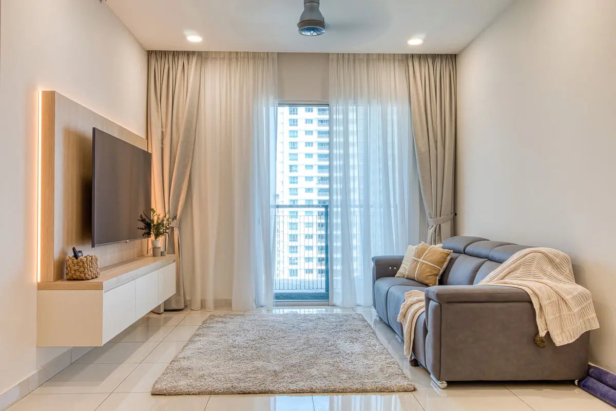 Living room with a wall-mounted TV on a backlit panel, grey sofa and balcony window