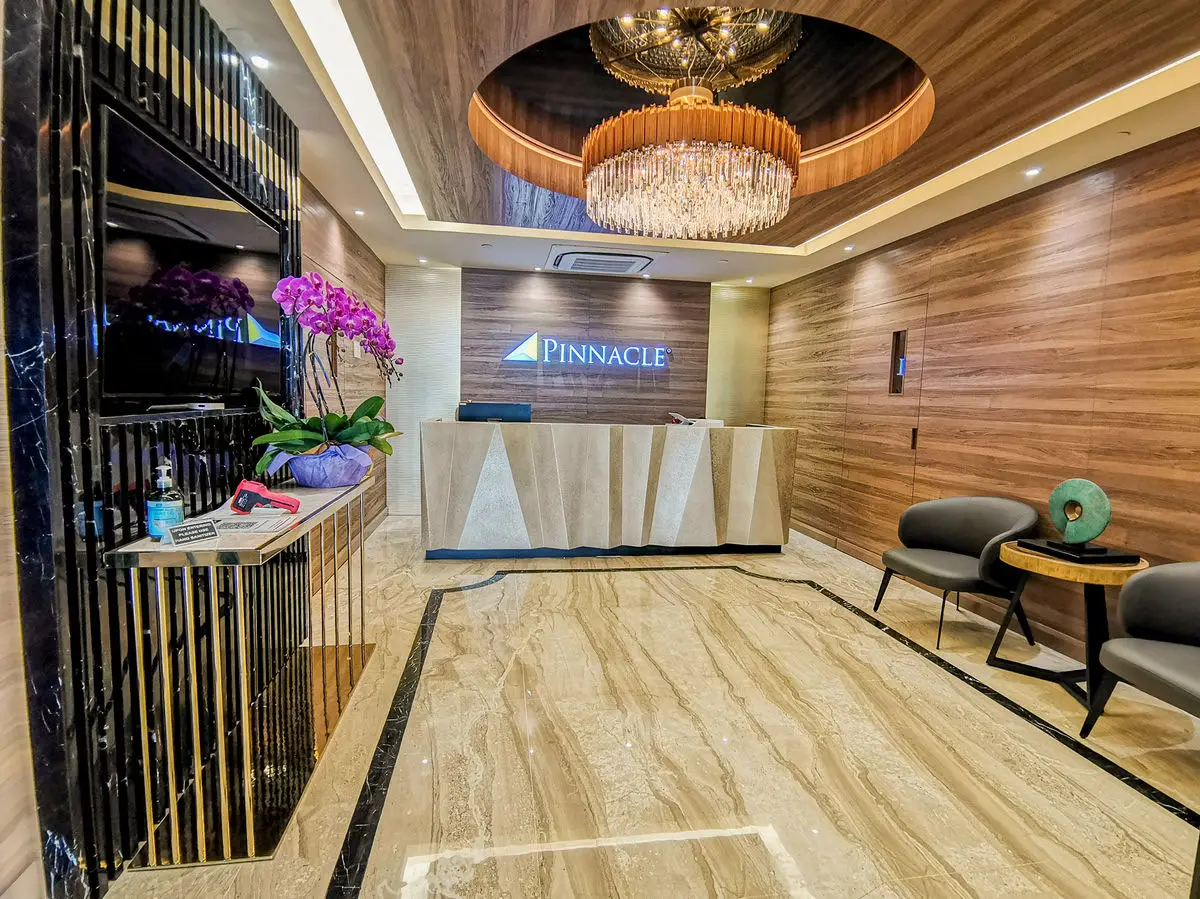 Reception with a stone counter, timber panelling and a ring chandelier