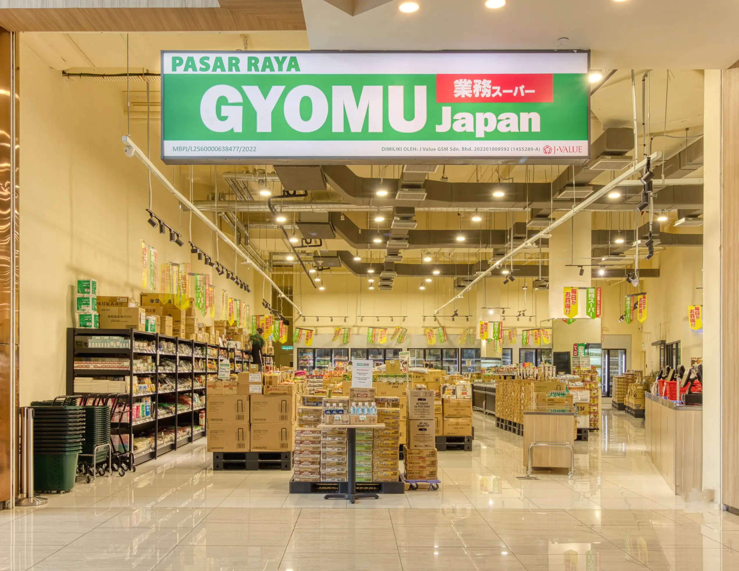 Gyomu Japan supermarket entrance with green lightbox sign, exposed services and pallet displays