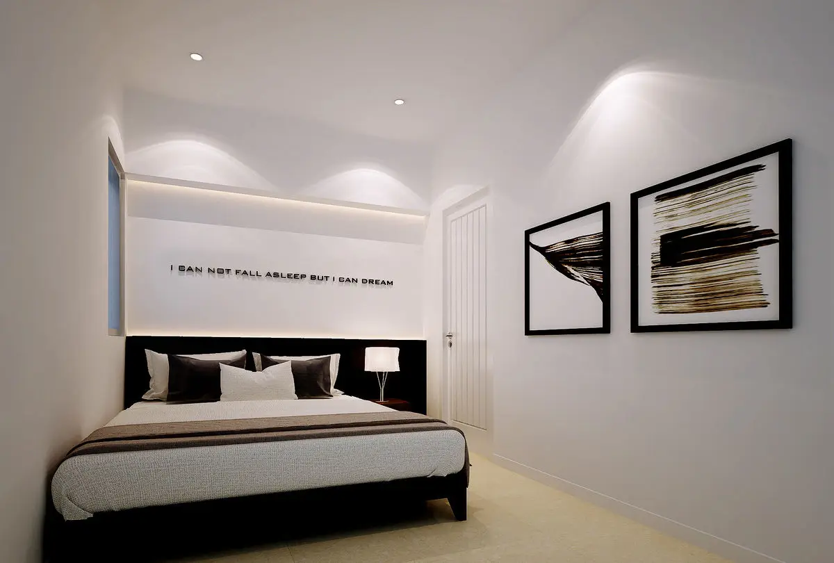 Bedroom with a backlit headboard niche, dark bedding and framed prints