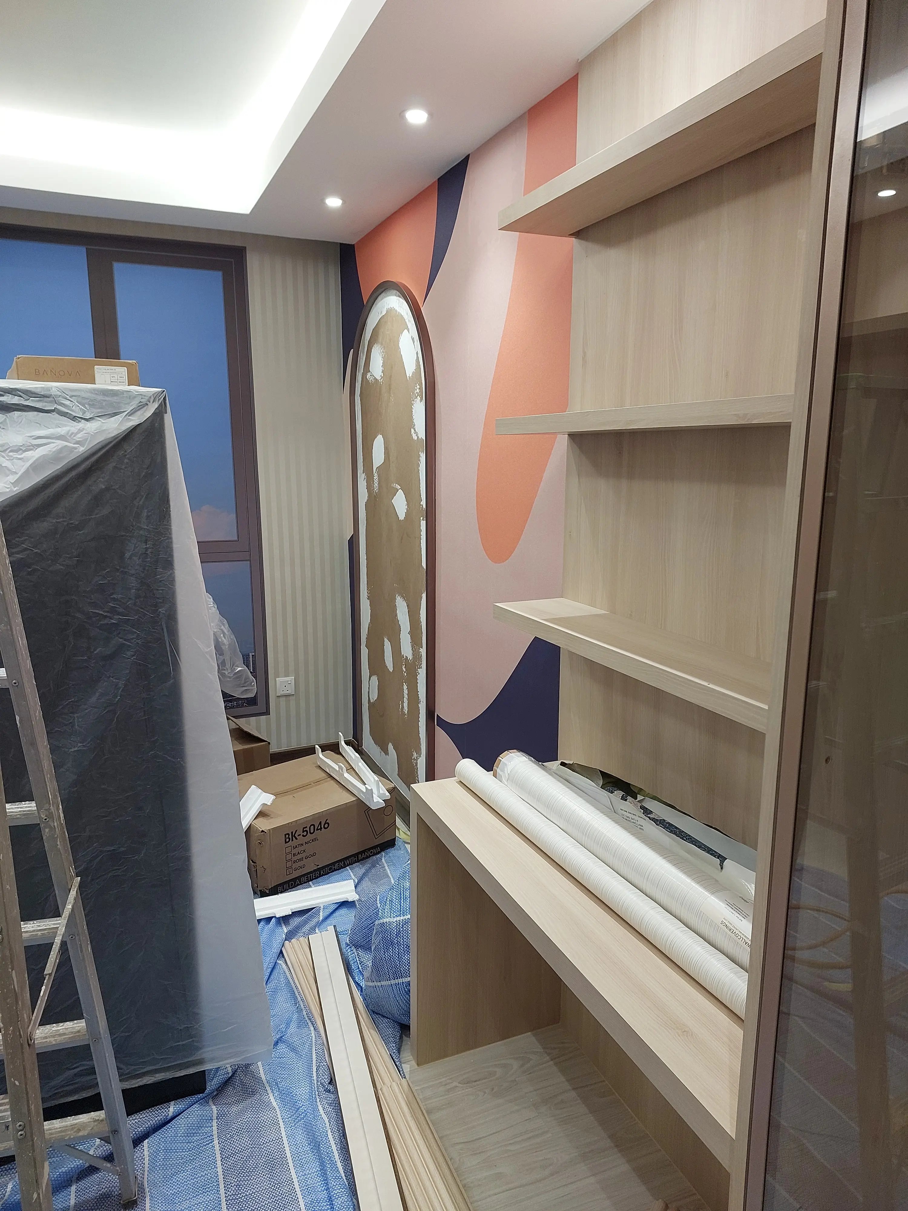 Coral, pink and navy mural wall with filler-patched oval bulkhead, slatted shelving and wallcovering rolls