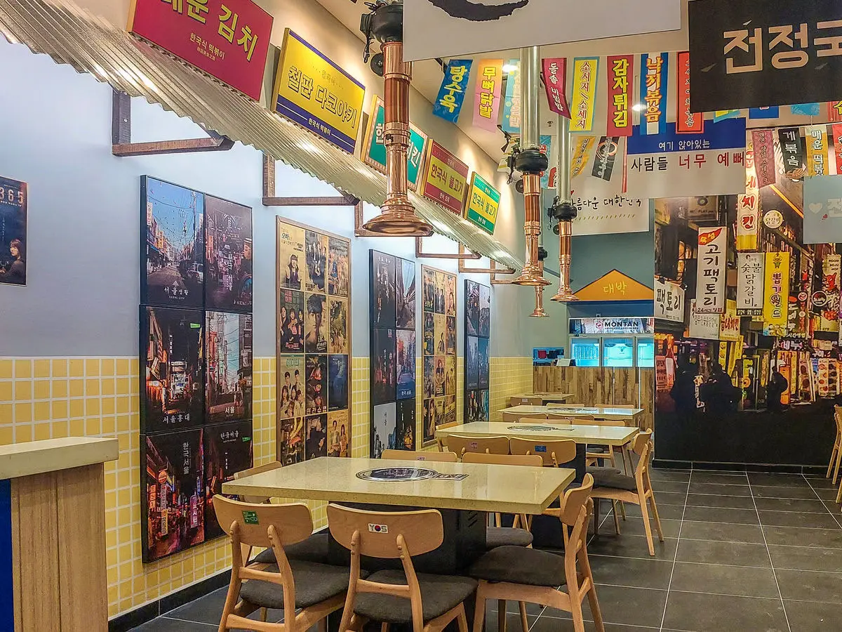 Dining area with layered Korean signage, brick walls and grill tables
