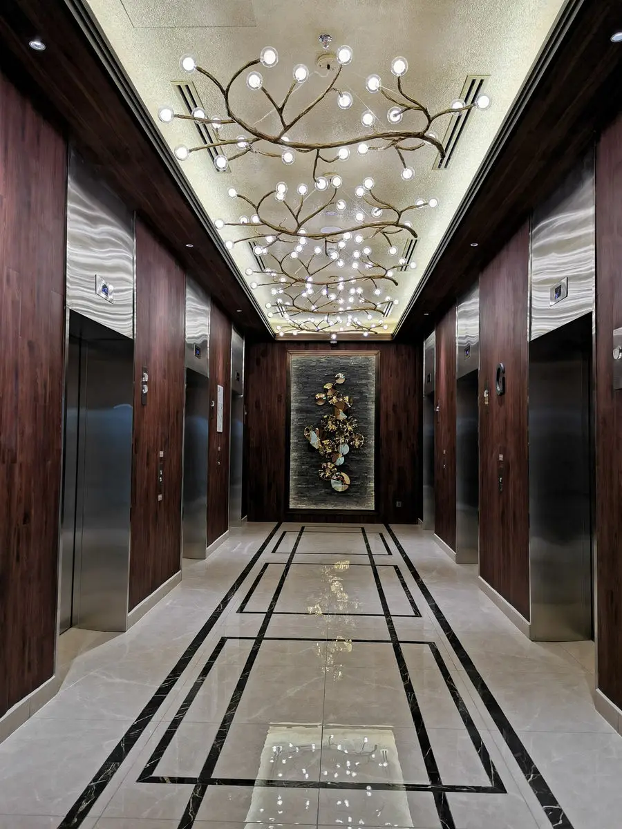 Lift lobby with timber-panelled walls, a chandelier and inlaid flooring
