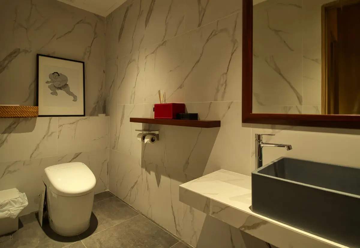 Washroom in white marble with a black vessel basin and timber shelf