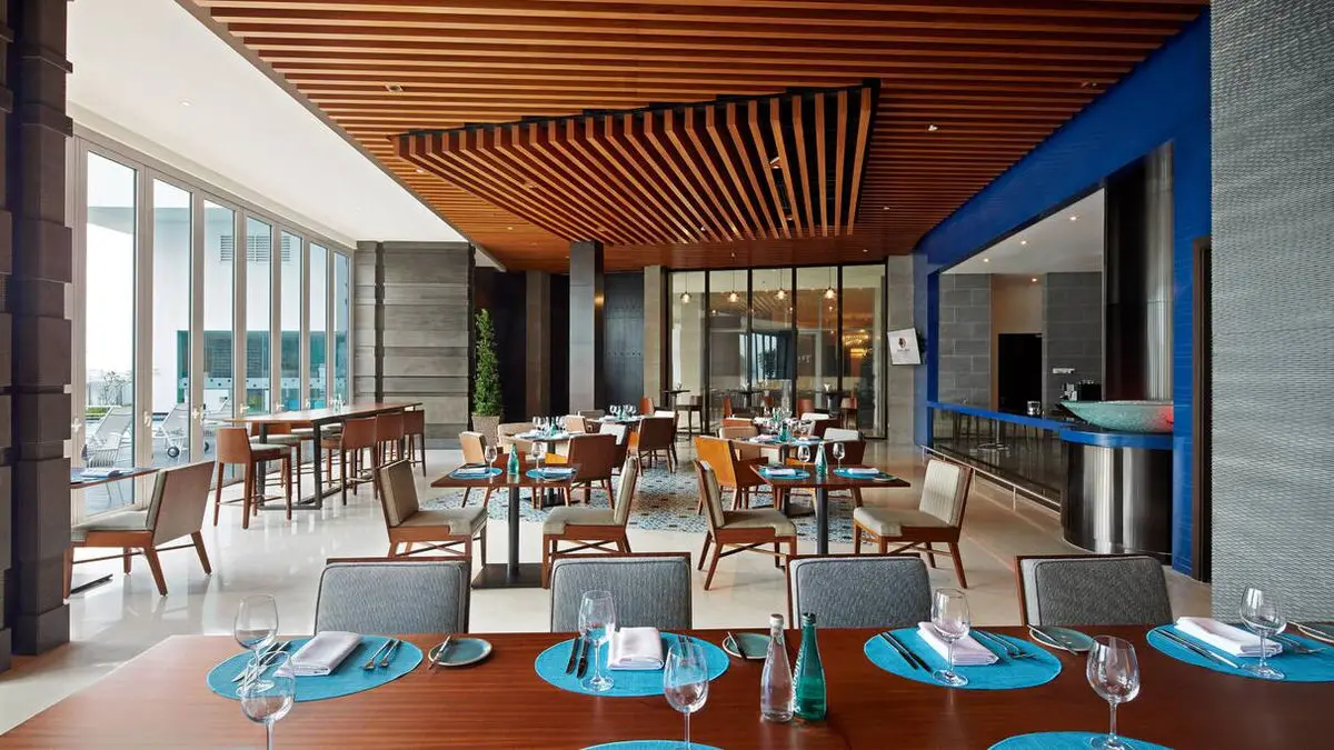 Hotel restaurant with a timber slatted ceiling, blue banquettes and set tables