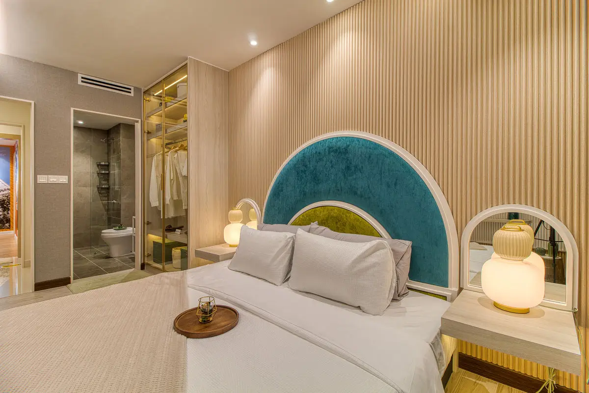 Bedroom with a teal arched headboard, bedside lamps and a walk-through wardrobe