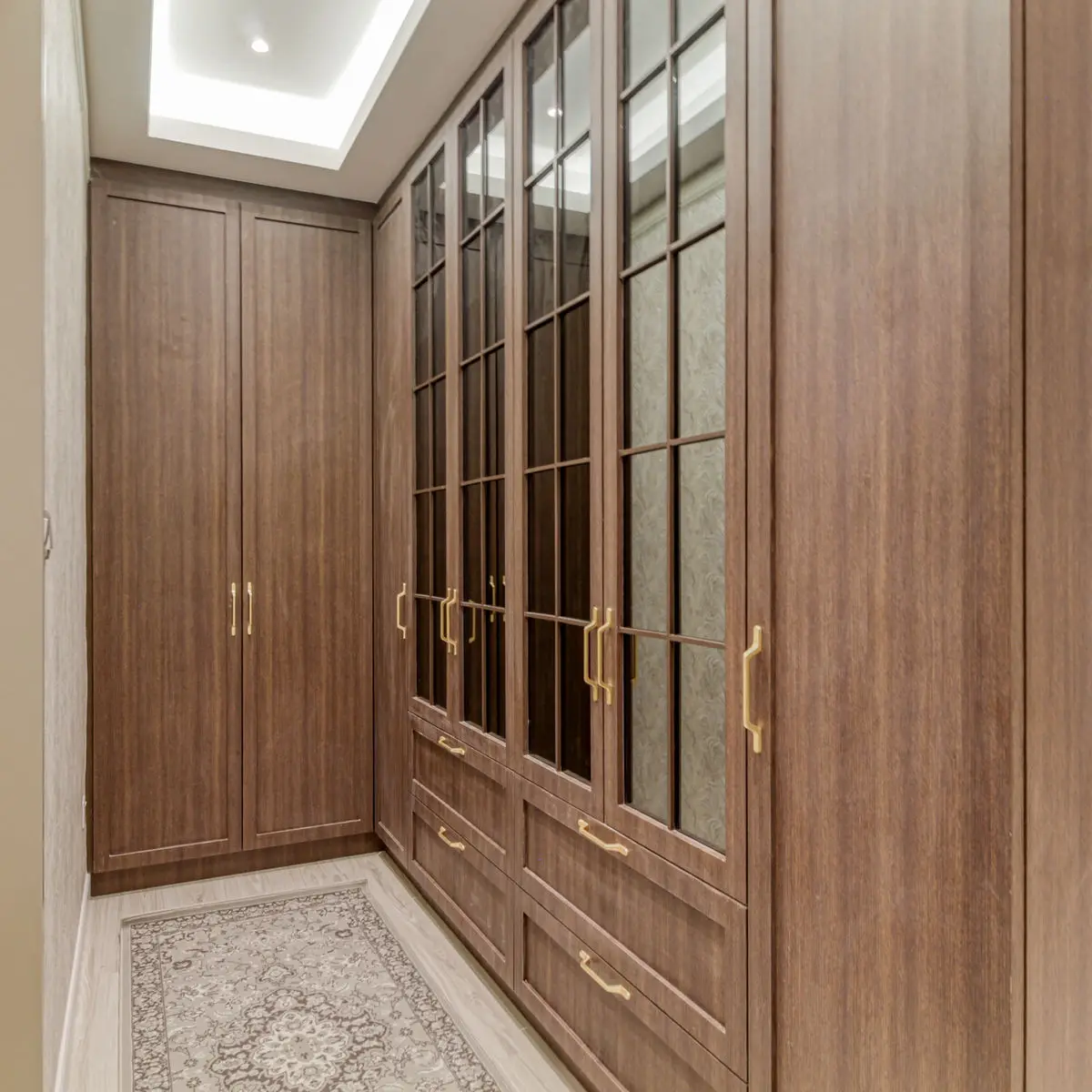 Timber wardrobe run with glazed upper doors and brass handles