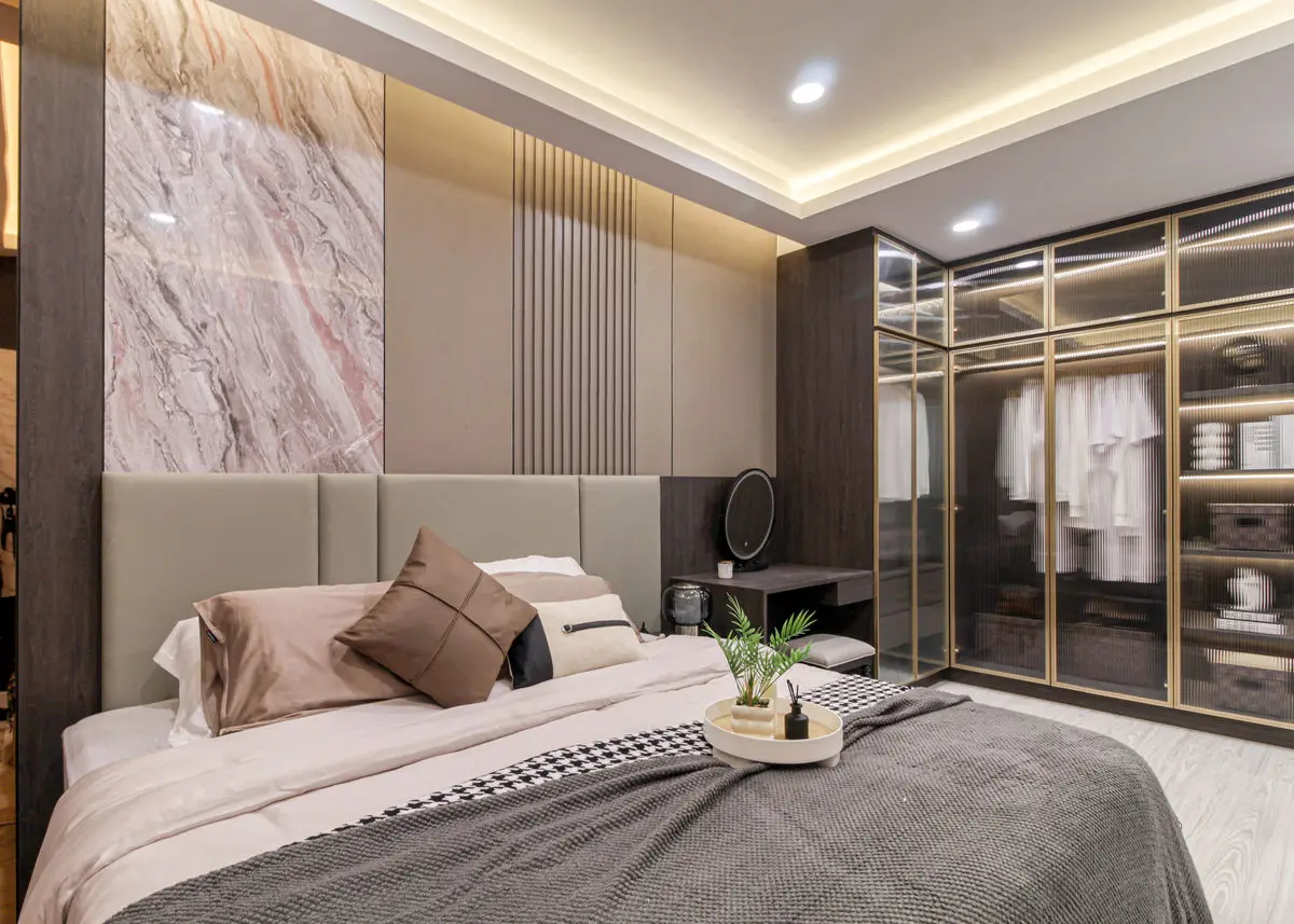 Bedroom with a marble feature wall, upholstered headboard and mirrored wardrobe