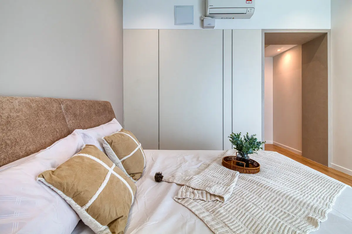 Bedroom detail with cushions on white bedding and a wardrobe run behind