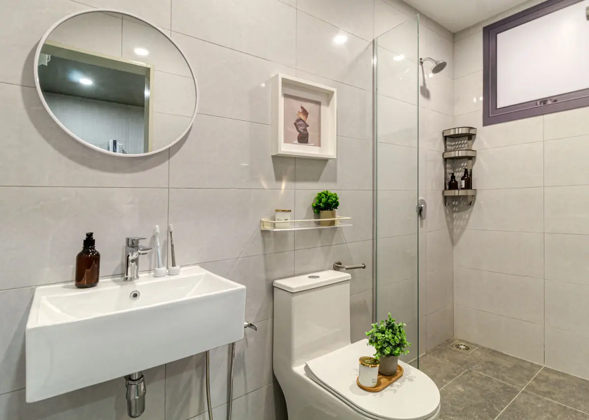 Bathroom with a wall-hung basin, round mirror and glass shower screen