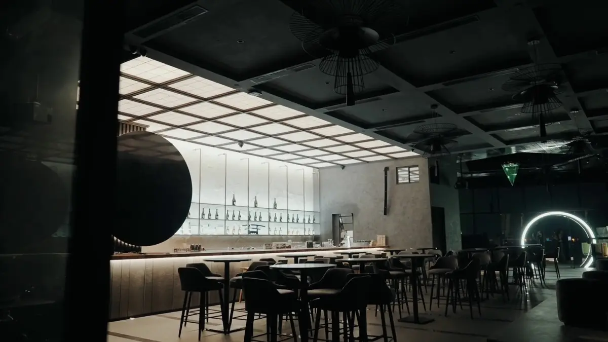 Bar counter with stools, a dark curved feature and a green neon accent