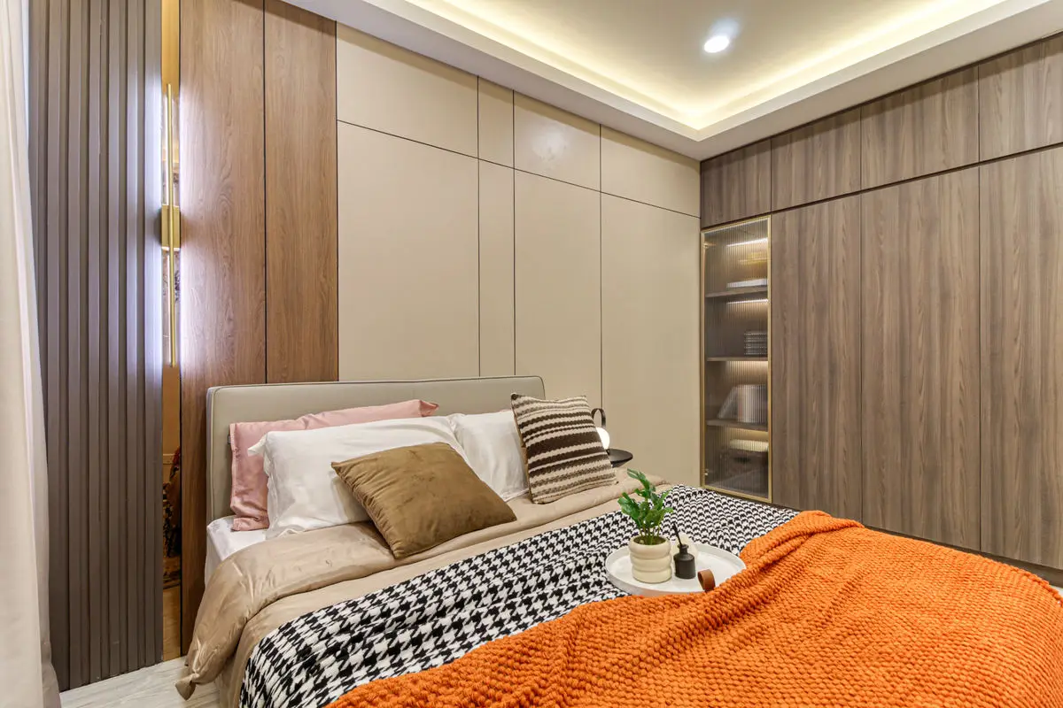Bedroom with a timber wardrobe run, upholstered headboard and patterned bedding