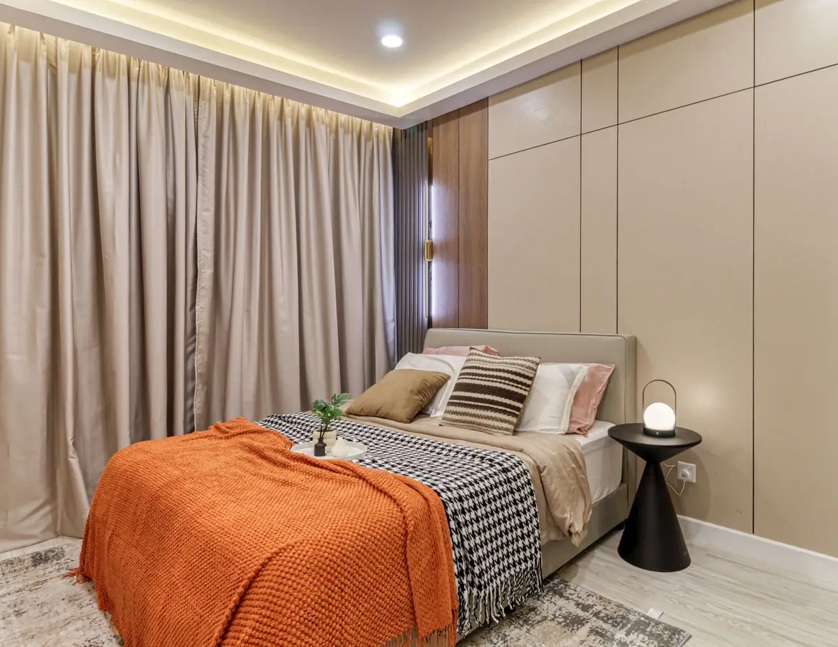 Bedroom with full-height curtains, built-in wardrobes and an orange throw