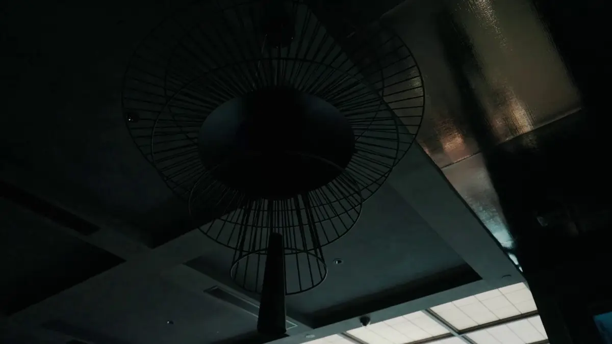 Ceiling detail with a black fan-shaped light fitting against a grid ceiling