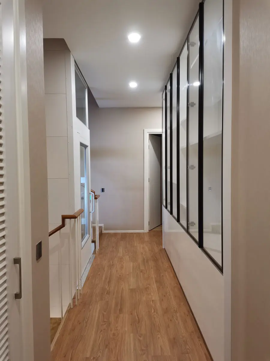 Upstairs corridor with a black-framed glass partition and wood flooring