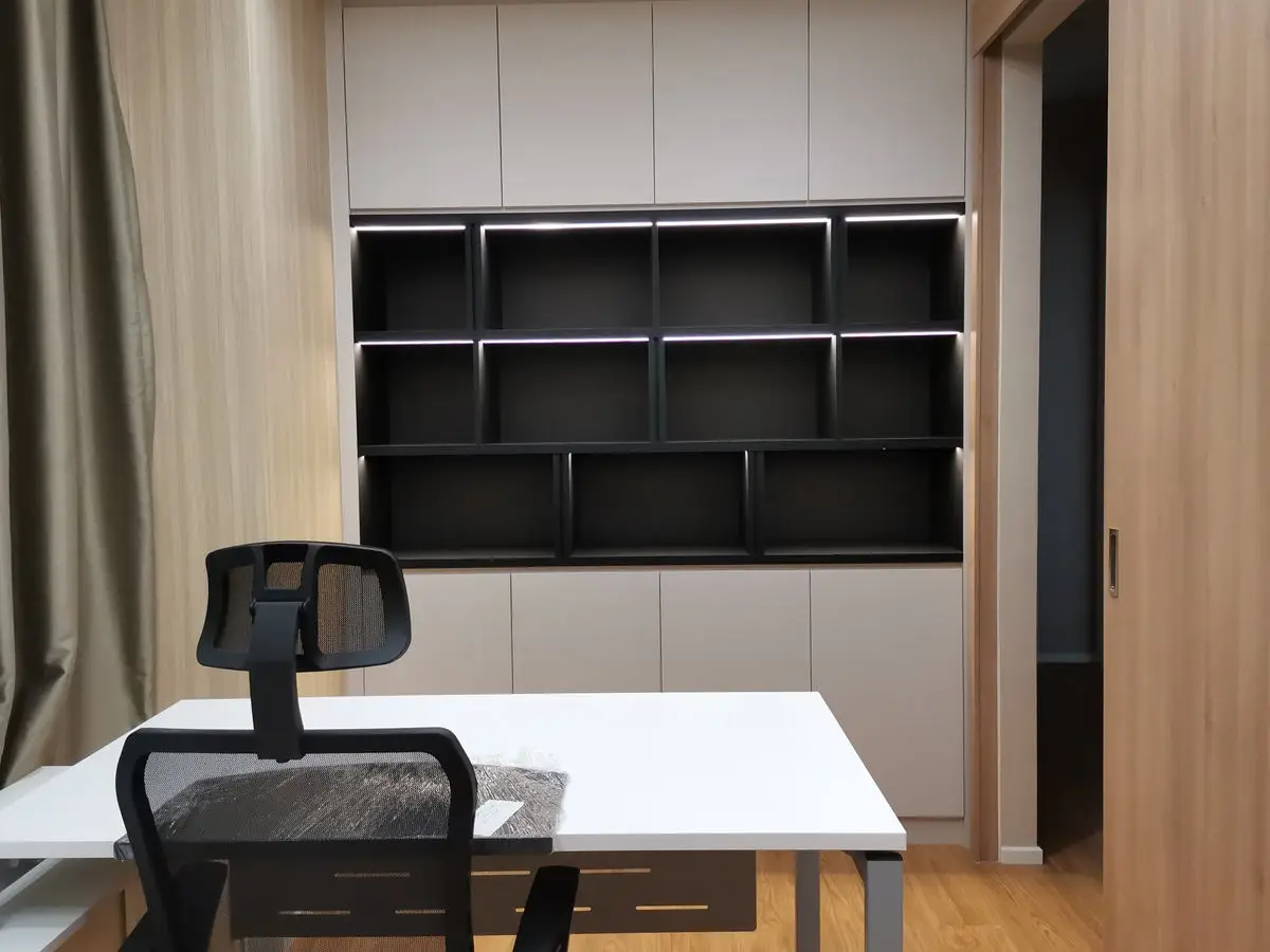 Study with black wall-mounted shelving, a white worktop desk and an office chair