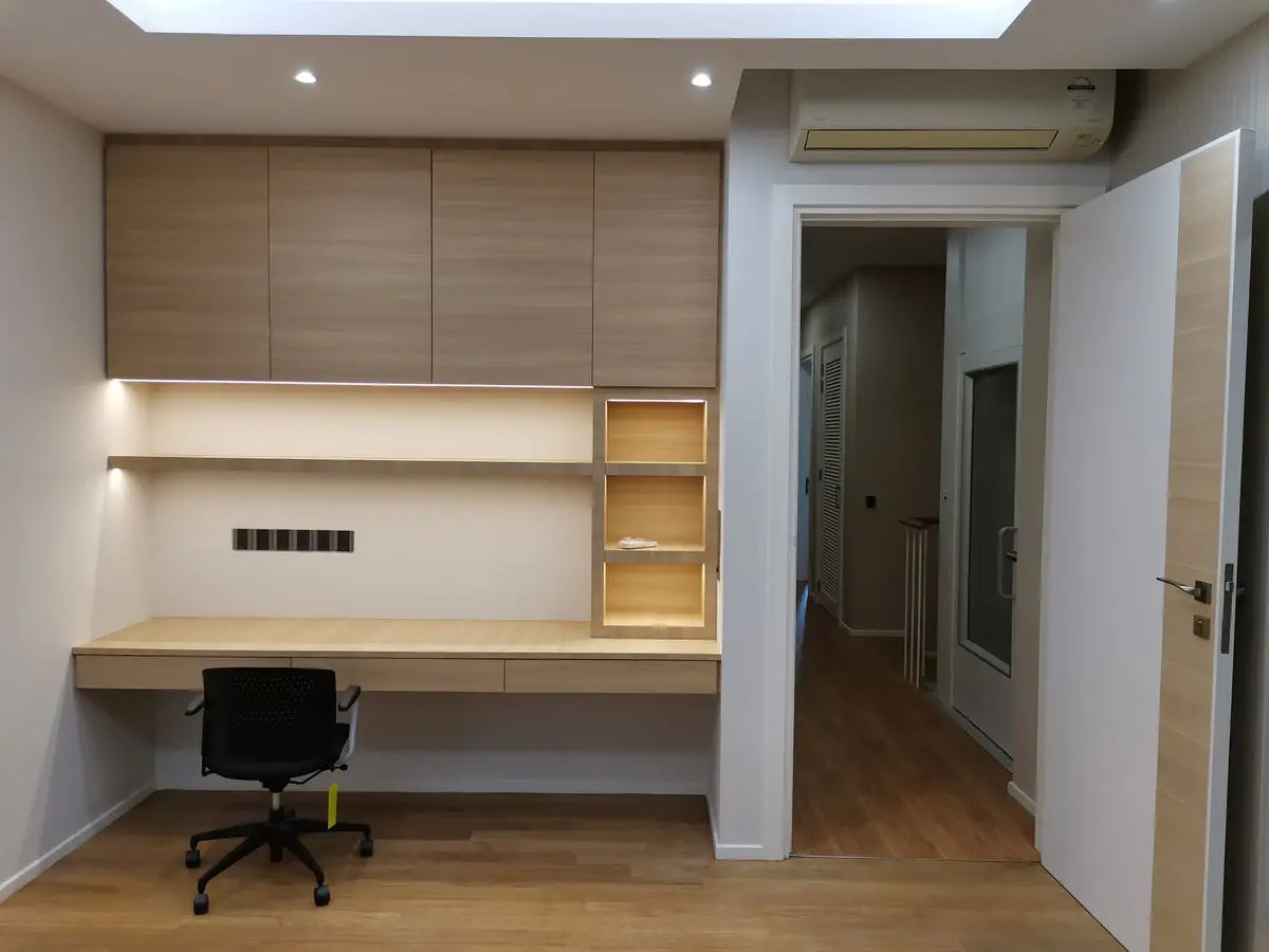 Built-in study nook with a timber desk, overhead cabinets and open shelving